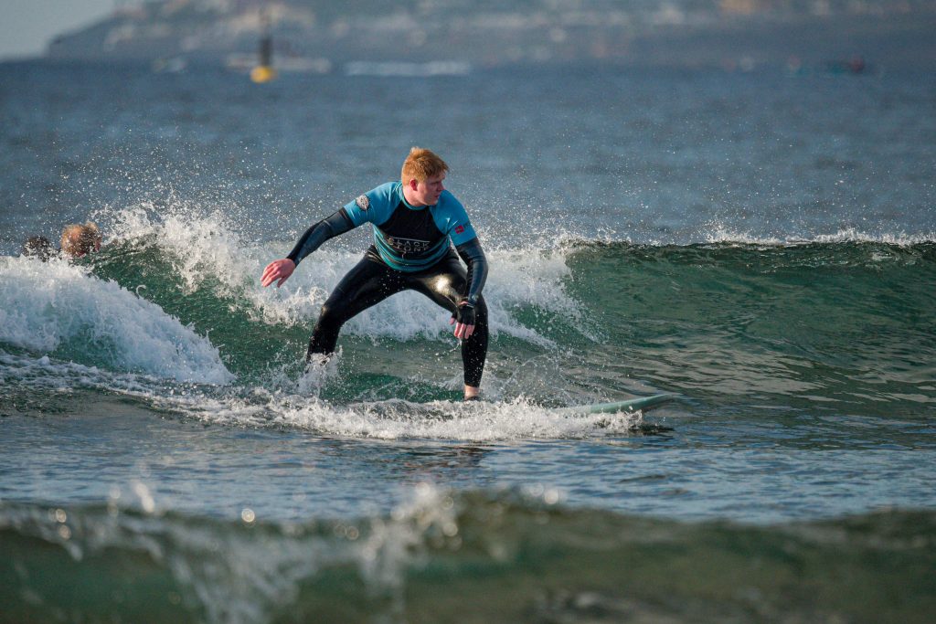 Blackstone Surf Center woman student surfing in El Medio in Playa las Américas Tenerife during a surf lesson