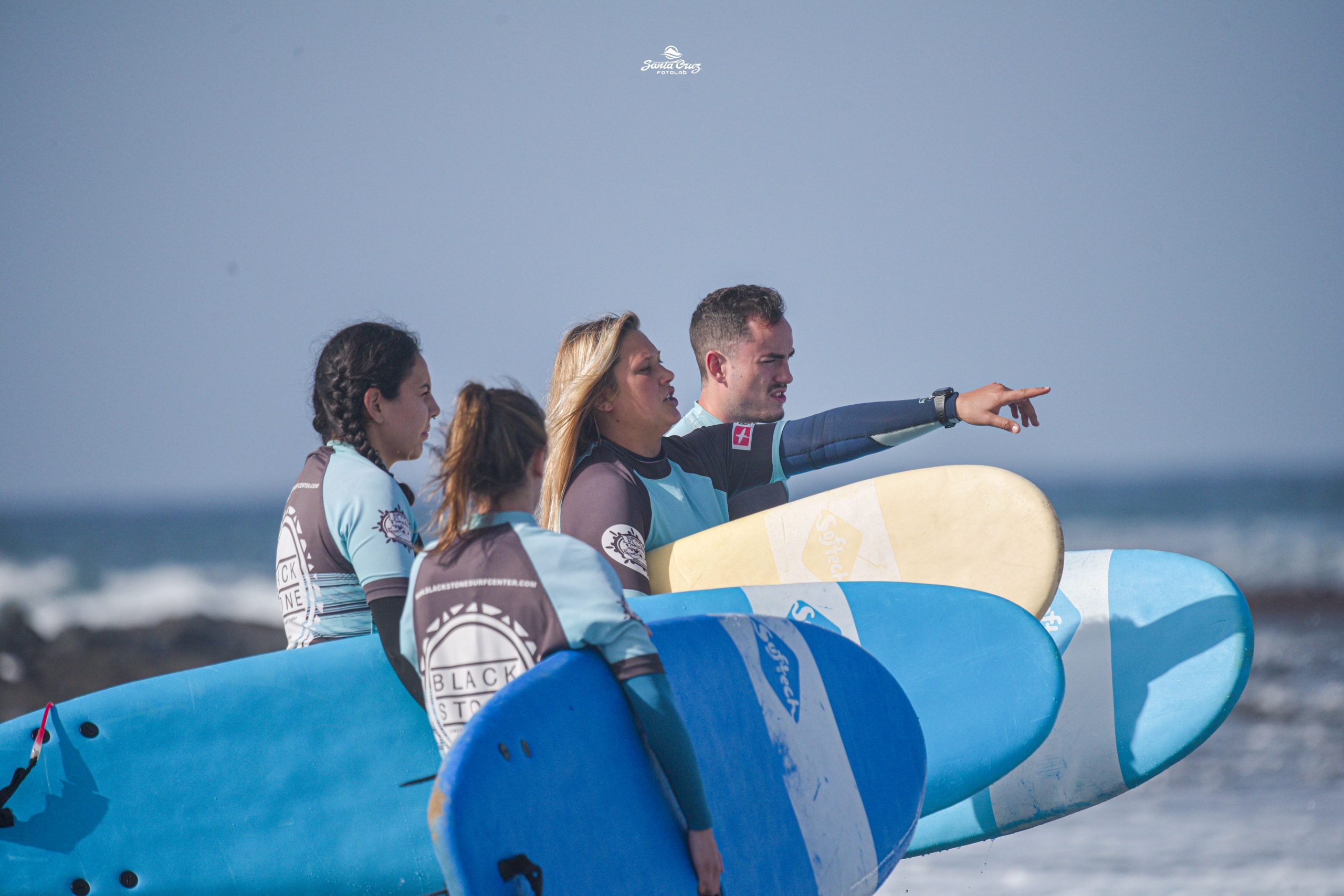 Blackstone Surf Center group of students with woman instructor in Playa las Américas in Tenerife before a surf lesson