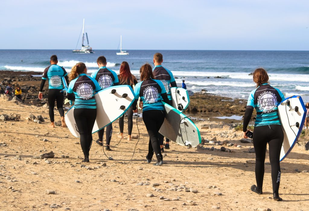 Blackstone Surf Center students with surf equipment in Playa las Américas in Tenerife during a surf lesson