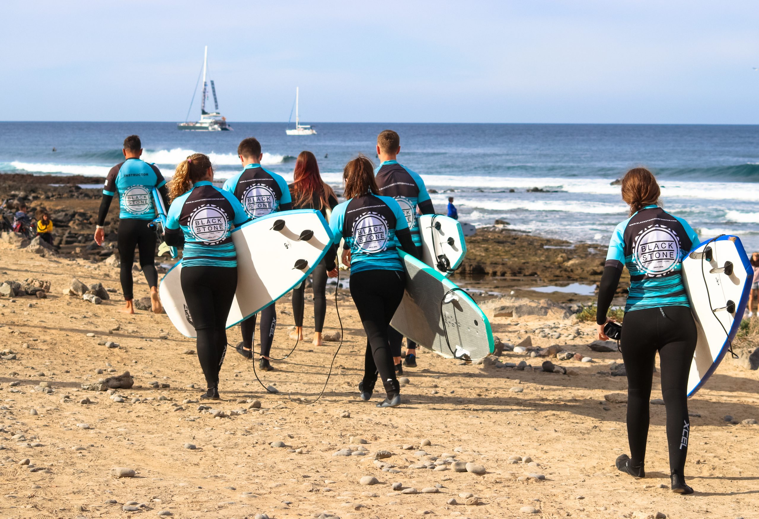 Blackstone Surf Center students with surf equipment in Playa las Américas in Tenerife during a surf lesson